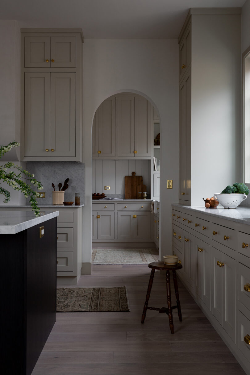 white kitchen space dimly lit looking through to a. butler's pantry