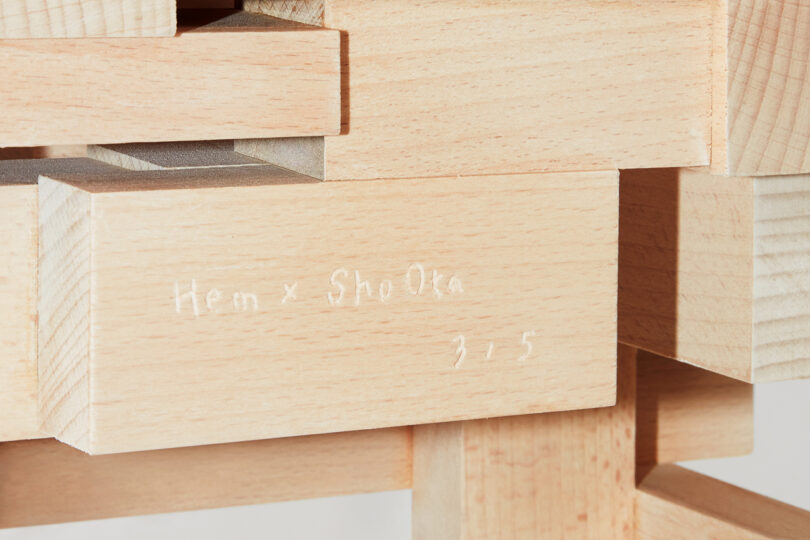 detail of wood stool made of squared off pieces of wood with Hem X Sho Ota written on it