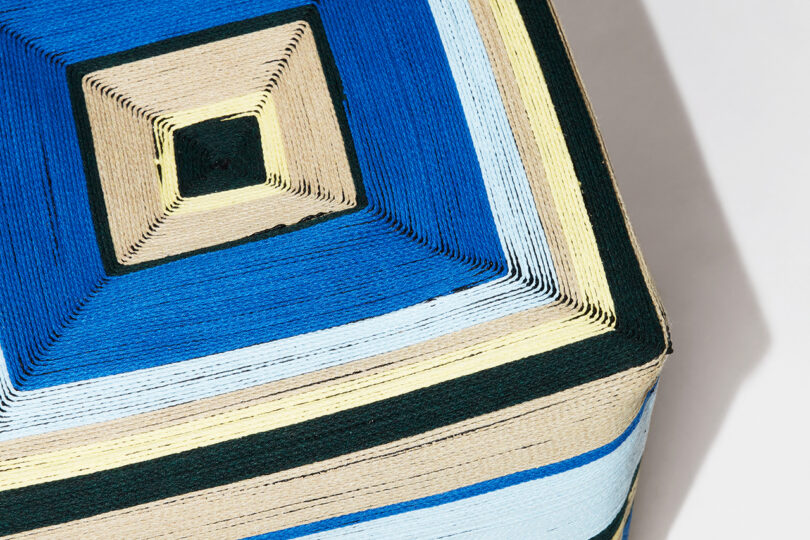 detail of square stool with blue, black, yellow, and tan stripes