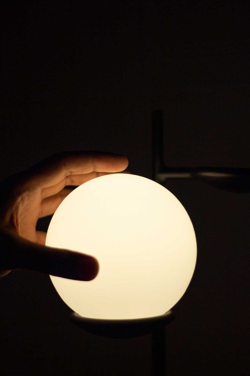 closeup of a hand on a lit up globe in darkness