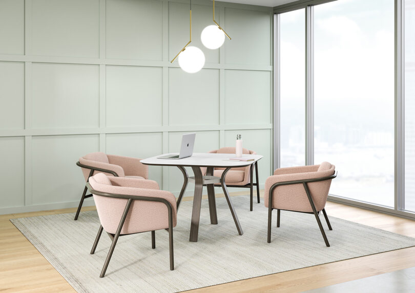 four pink and wood armchairs surround a round table with four legs in a styled space