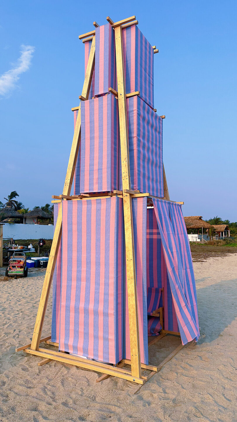 Striped pink and blue temporary shade structure installed on the beach at Casa Naila. 