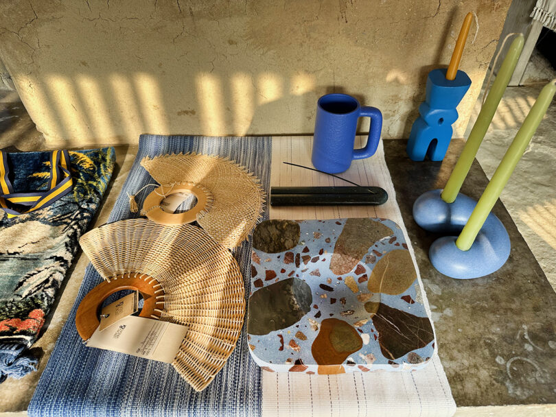 Display of design objects including woven fans, terrazzo ceramics, and candle holders.