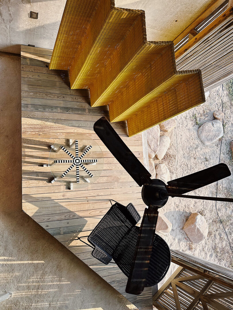 One of four main exhibition displays within Casa Naila curated by Carlos Torre Hütt photographed from above showing checkered round table, woven armchair and woven room divider.