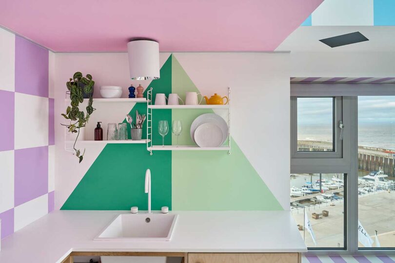 small kitchen interior with one wall in purple and white checkered design and one with two tone green triangle