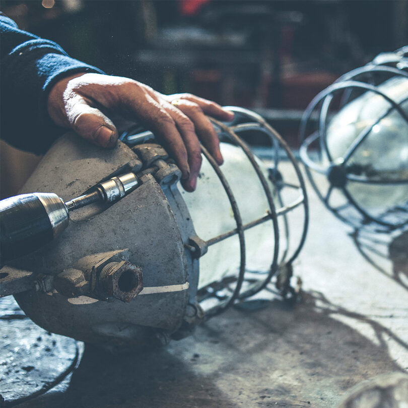 A white hand holds a vintage industrial light