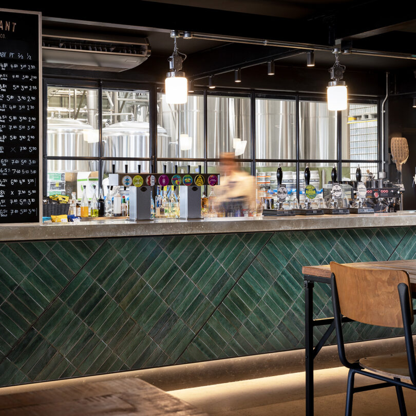 A set of pendant lights hangs above a green-tiled bar